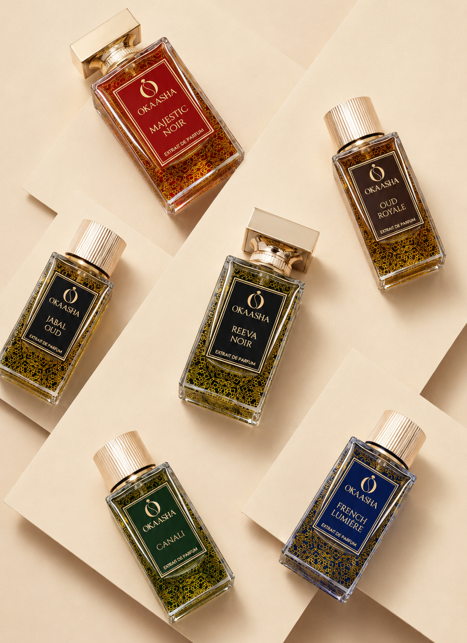 Six rectangular perfume bottles from Orkasha arranged on beige paper sheets. The bottles contain scented liquids in amber, green, and blue tones and are topped with gold caps.
