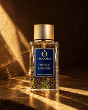 A bottle of Okaasha French Lumière extrait de parfum stands on a stone surface with dramatic warm sunlight and shadows.