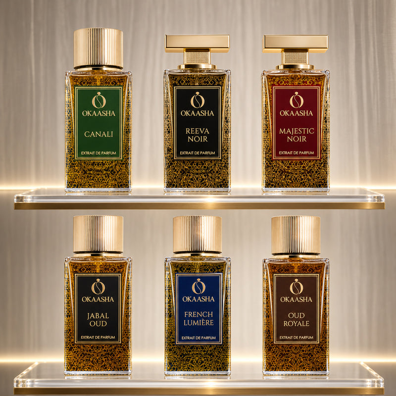 Six Okaasha perfume bottles arranged on two clear acrylic shelves against a softly lit beige curtain background.